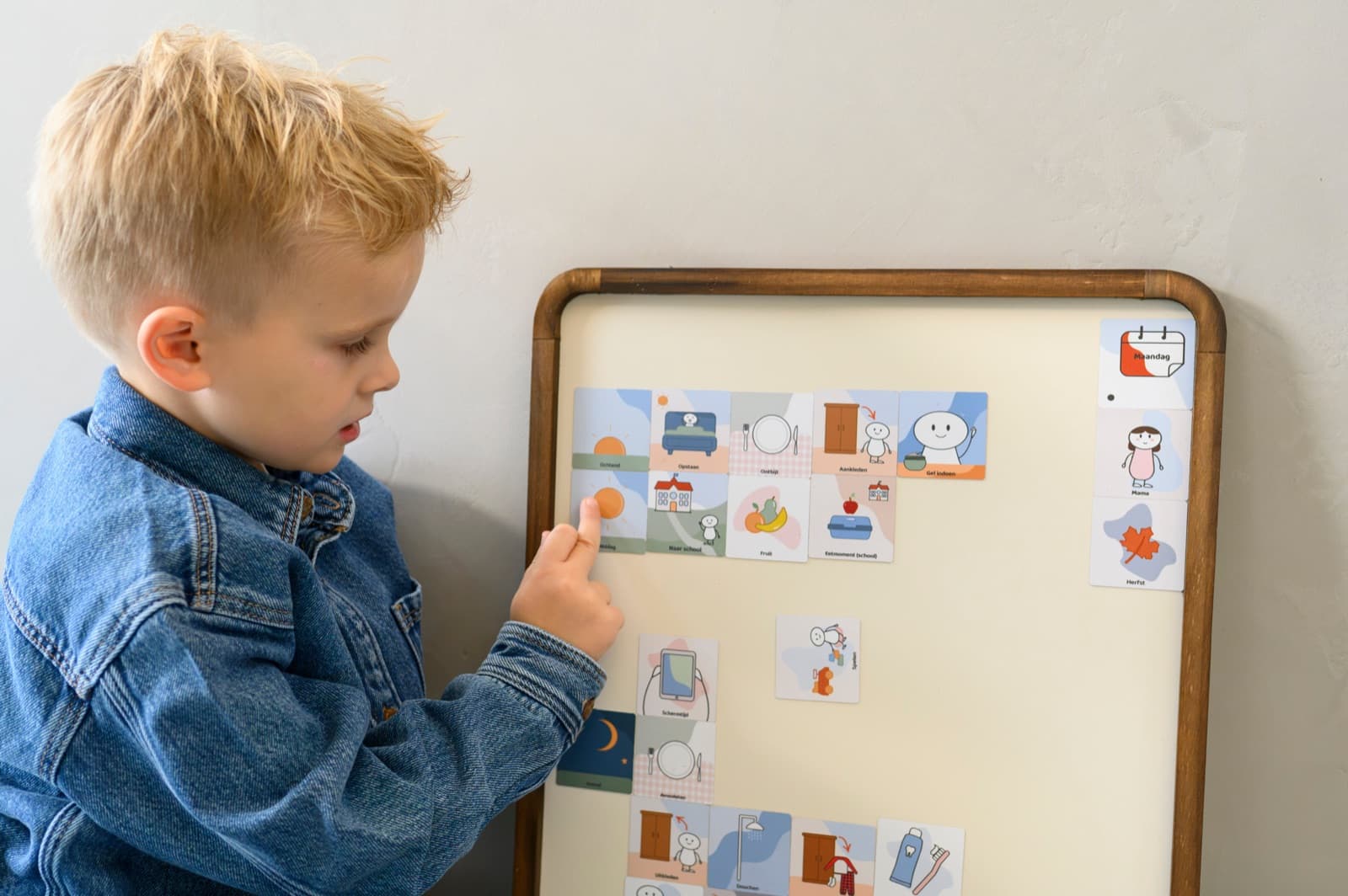 Een kind wijst op het magneetbord naar het volgende plaatje in de ochtendroutine.