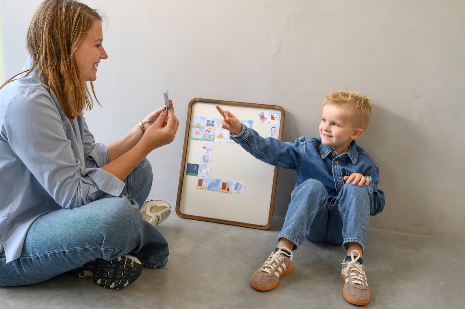 Een begeleider laat een pictogram zien. Het kind wijst naar het dagritme op het magneetbord.