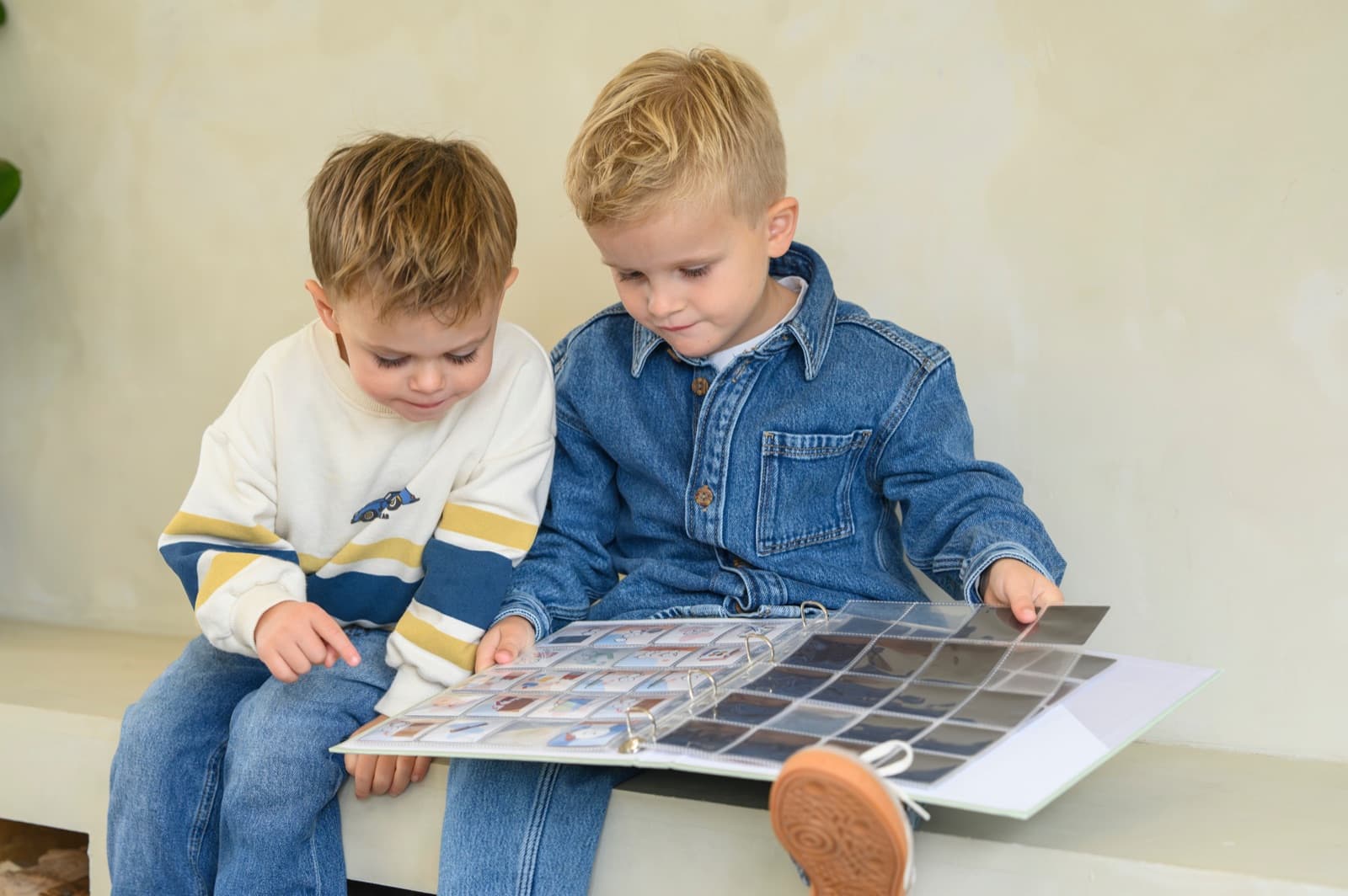 Twee kinderen zitten naast elkaar en bekijken samen de pictogrammen in de multomap.